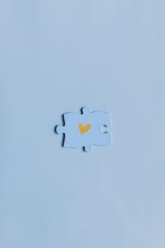 A close-up shot of a single blue puzzle piece with a yellow heart on a matching background.